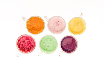 Top view of fresh fruit smoothies in glass cups isolated on white