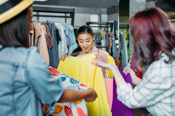 asian hipster girl with friends choosing clothes in boutique, fashion shopping girls concept