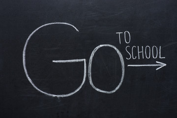 phrase go to school with arrow sign on black chalkboard