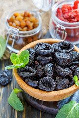 Wooden bowl and glass jars with dried fruit.