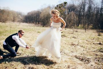 Wind blows bride's dress while she poses with groom on the lawn
