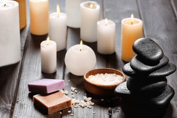 Close-up view of piled spa stones and candles with sea salt on wooden table top