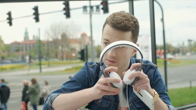 Man sitting in the city and starts listening music, steadycam shot
