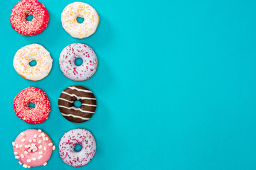 Overhead view of colorful donuts isolated on blue. Sweet background of donuts in minimalist style