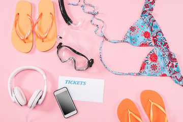 Group of women's casual outfits with gadgets and snorkeling equipment on pink background. Summer vacation concept