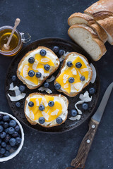 Sweet berry crostini sandwiches with ricotta mango blueberries and coconut chips on the whole grain bread