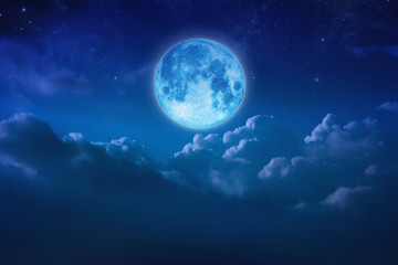 Beautiful blue moon behind cloudy on sky and star at night. Outdoors at night. Full lunar shine moonlight over cloud at nighttime with copy space background for headline text and graphic design.
