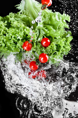Close-up view of fresh ripe cherry tomatoes with lettuce and water drops isolated on black, harvest vegetables concept