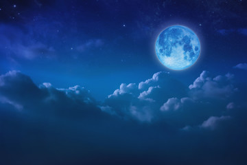 Obraz na płótnie Canvas Beautiful blue moon behind cloudy on sky and star at night. Outdoors at night. Full lunar shine moonlight over cloud at nighttime with copy space background for headline text and graphic design.