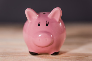 Close-up view of pink ceramic piggy bank on wooden table top, piggy bank savings concept