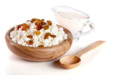 Cottage cheese with raisins and sour cream in a wooden bowl isolated on a white background