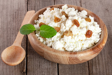 Cottage cheese with raisins in a wooden bowl on a wooden background