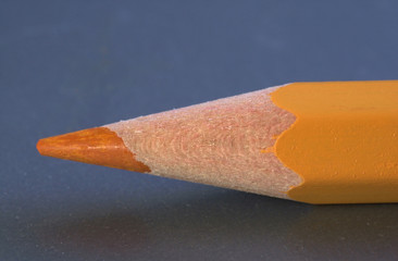 The tip of an ochreous pencil isolated on a dark background.