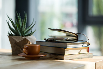 Close-up view of books, notebook with pencil and cup of coffee on wooden table