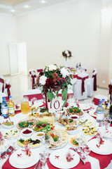 The vase with flowers and frame with number standing on the table