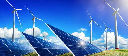 Solar panels and wind turbines on open field, with nice blue sky, white clouds and the reflection...