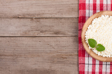 Cottage cheese in a wooden bowl on old wooden background with copy space for your text. Top view