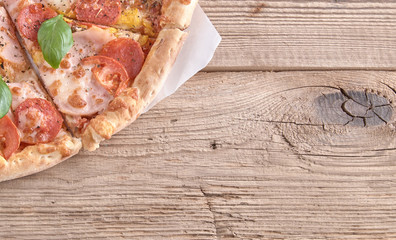 Delicious fresh pizza with ham and tomato on a wooden background. Top view.