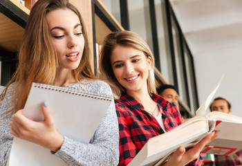 Concentrated two young ladies students reading book