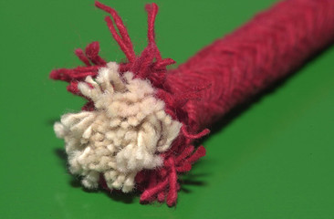 A red piece of rope used to light fireworks isolated on a green surface.