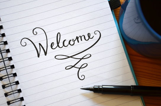 "WELCOME" in brush calligraphy on notepad