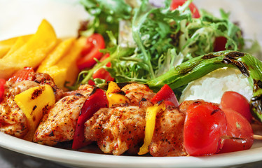 Chicken skewers, french fries and rice with leaf vegetable.