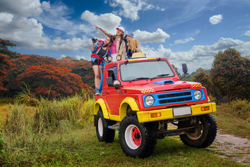woman enjoy on the traveling adventure on the rack-back of the convertible off-road car by taking the picture in the jungle background