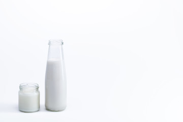 organic coconut oil in glass jar and coconut milk in glass bottle isolated on white, coconut drink concept