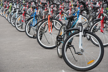 A row of a large number of bicycles with wheels on the town square in summer