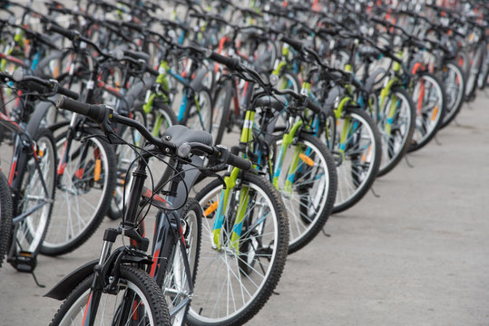 A row of a large number of bicycles with wheels on the town square in summer
