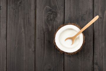 top view of ripe coconut half with milk and wooden spoon, coconut milk