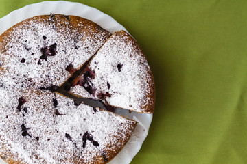 Homemade cake on a white plate on green colored fabrics