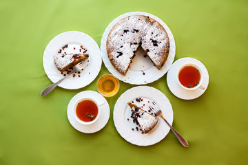 Tea drinking. Homemade cake on a white plate on green and orange colored fabrics