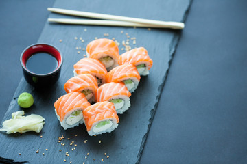 Philadelphia roll classic on a dark stone background. Philadelphia cheese, cucumber, avocado. Japanese sushi. Top view