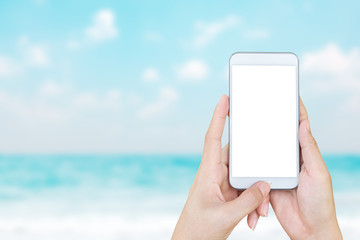 Woman's hand holding smart phone with blur beach and tropical sea.