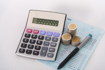 Increasing columns of coins, piles of coins arranged as a graph and calculator with pen on white background