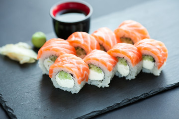 Philadelphia roll classic dark stone on the Board. Salmon, Philadelphia cheese, cucumber, avocado. Japanese sushi.