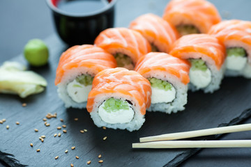 Philadelphia roll classic dark stone on the Board. Salmon, Philadelphia cheese, cucumber, avocado. Japanese sushi.