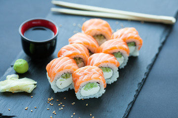 Philadelphia roll classic dark stone on the Board. Salmon, Philadelphia cheese, cucumber, avocado. Japanese sushi.