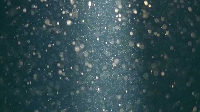 Abstract blue background with beautiful golden flickering particles. Underwater bubbles in flow with bokeh. 3840x2160