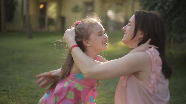 Daughter rushes into mother's arms in the park and gives her a big hug.