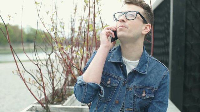 Happy man in denim jacket chatting on cellphone, steadycam shot
