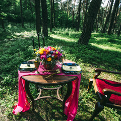 decorated wooden table served for two in the garden on grass on the riverbank. Boho and rustic...