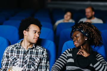 Obraz premium Beautiful mixed race couple flirting at the movies