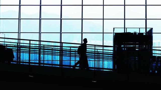 Sunset airport terminal hall. Walking travelers silhouettes.
