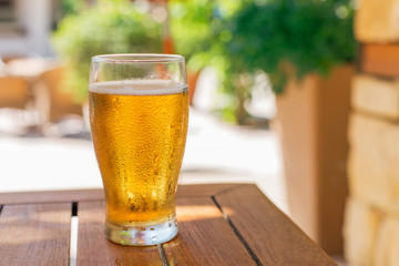 Glass of light beer on the wooden table.
