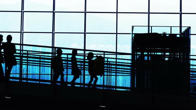 Sunset airport terminal hall. Walking travelers silhouettes.