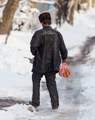 Homeless man is walking on the road in winter