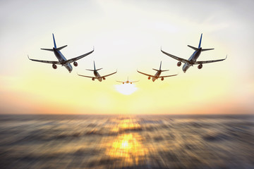 Airplanes or aircraft flying on the blur motion sea, ocean at sunrise in the morning as transportation, business, travel, goal, target, mission, complete and success concept.