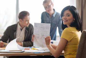 Joyful positive woman holding an engineering drawing